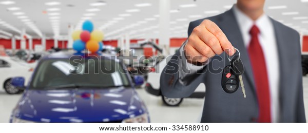 Hand with a car key. Auto dealership and\
rental concept background.