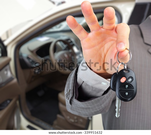 Hand with a car key. Auto dealership and\
rental concept background.