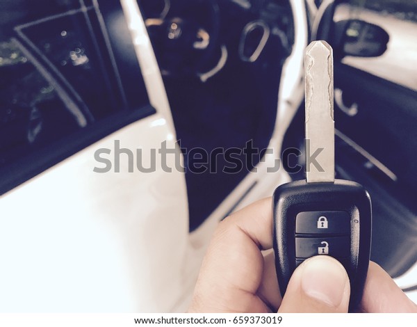 Hand with a car key\
with car on background