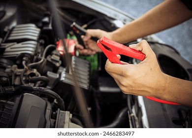 Hand car mechanic holding car booster cables for jump start car for empty battery dead and low voltage power problem or fix and service maintenance accident assistance engine doesn't start. - Powered by Shutterstock