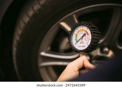 Hand car mechanic holding car tire pressure check equipment tool to checking low tire pressure inflating tires to or refill or air inflate to safety and car care service maintenance inspection. - Powered by Shutterstock