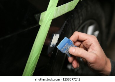 Hand Of Car Service Worker Spackles A Small Dent On The Bumper Of The Car. Shpatel Is Putting Filler On The Dent