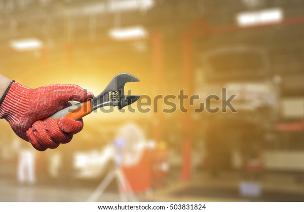 Hand of car technician with a wrench working in auto\
garage with vintage tone