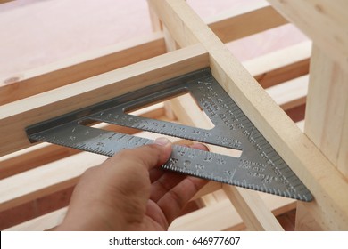 Hand of carpenter is measuring angle of wooden furniture