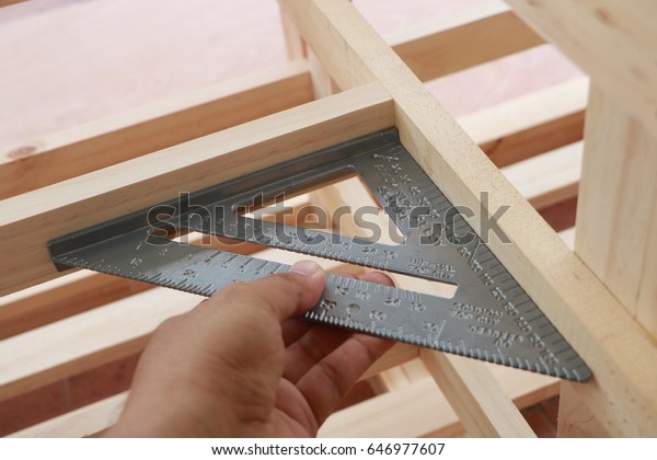 Hand\
of carpenter is measuring angle of wooden\
furniture