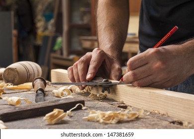hand of a carpenter taking measurement of a wooden plank