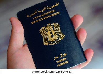 A Hand Carrying A Syrian Passport