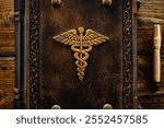 Hand carved and gilded the Caduceus symbol placed to the aged brown leather book