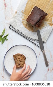 Hand Catching A Piece Of Carrot Cake On A Blue And White Plate On A Marble Worktop. Overhead View