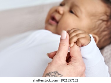 Hand of caucasian mom, foster single parent holding hand of cute adorable infant african american baby girl adopted daughter as love, child care, diversity, charity and Mothers day concept. Close up
