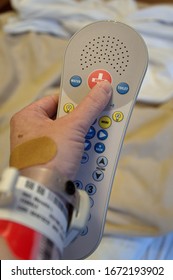 Hand of a caucasian patient pressing the call for nurse button in a hospital bed
