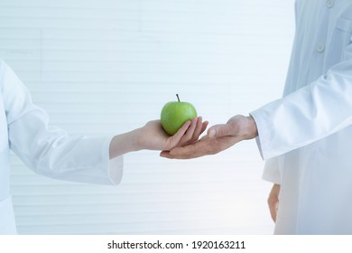 Hand Of The Caucasian Student Gave A Green Apple To The Science Teacher 