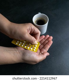 Hand Of A Caucasian Woman Pulling Out A Birth Control Pill To Take Along With Her Breakfast. Mention Of Medical Choices, Risks Of Becoming Pregnant, Misuse Of Coffee Recipes. Alternative Medicine.