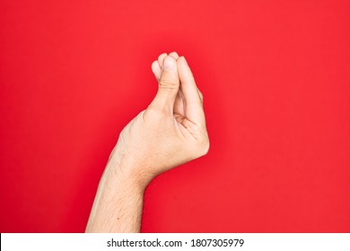 Mano de un joven caucásico que muestra el dedo sobre un fondo rojo aislado haciendo gesto italiano con los dedos juntos, movimiento de gestos de comunicación