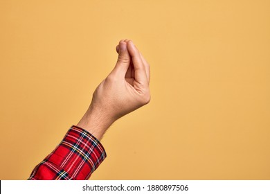 Mano de un joven caucásico que muestra dedos sobre un fondo amarillo aislado haciendo gesto italiano con los dedos juntos, movimiento de gestos de comunicación