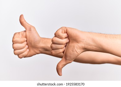 Hand of caucasian young man showing fingers over isolated white background showing disagree and agreement with thumbs up and thumbs dow, mixed emotions idea