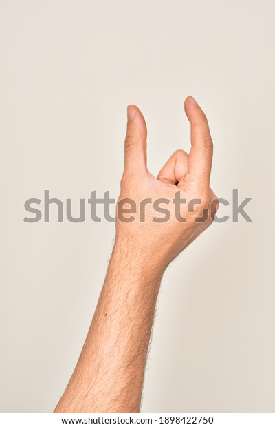 Hand of caucasian young man showing\
fingers over isolated white background picking and taking invisible\
thing, holding object with fingers showing\
space