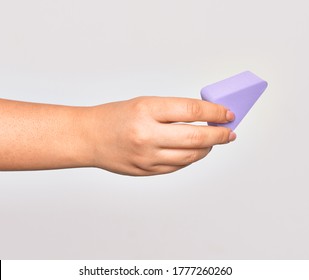 Hand of caucasian young woman holding purple makeup sponge over isolated white background