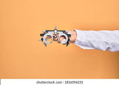 Hand Of Caucasian Young Woman Holding Optometry Glasses Over Isolated Yellow Background