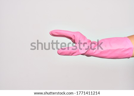 Hand of caucasian young woman wearing pink cleaning glove doing catch sign over isolated white background