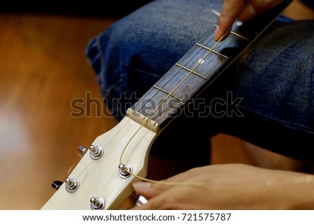 Mans’s Hand changing the acoustic strings guitar