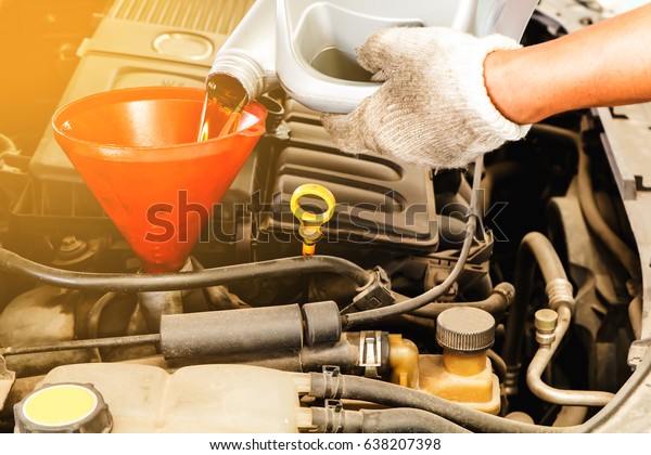 Hand changing motor oil to\
engine