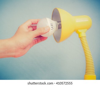 Hand Changing A Regular Light Bulb For LED,vintage Background