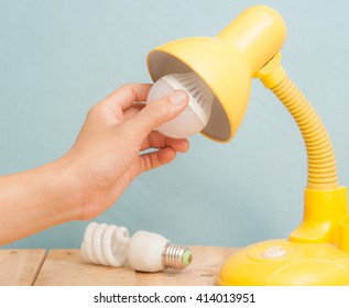 Hand Changing A Regular Light Bulb For LED,vintage Background