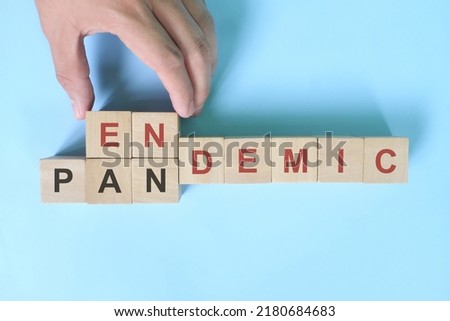 Hand changing word pandemic to endemic in wooden blocks. Covid-19 transition from pandemic to endemic concept.