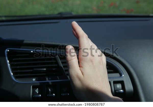 Hand checking\
the air conditioner in the\
car\

