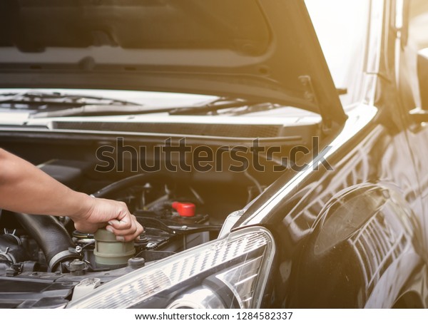 Hand checking car
engine before driving to travel. Mechanic with scan tool diagnosing
car in open hood. 
