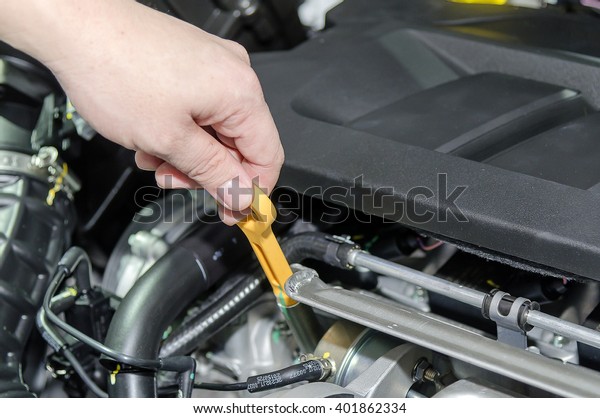 A hand Checking for\
engine oil on a car