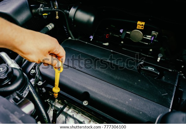 The hand checks the oil\
in the engine