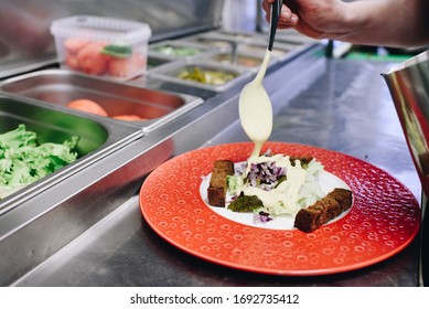 Hand Of Chef As He Or She Is Preparing A Salad In A Fancy Restaurant Kitchen