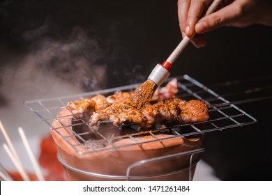 Hand Of Chef With Pork Grill Barbecue (ฺBBQ) With Seasonings Mala, Sichuan Pepper, Spices China Grilled On Charcoal Grill Stove, Black Background.