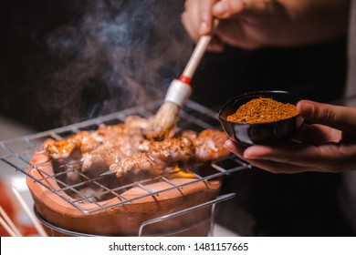 Hand Of Chef With Pork Grill Barbecue (ฺBBQ) With Seasonings Mala, Sichuan Pepper, Spices China Grilled On Charcoal Grill Stove, Black Background.