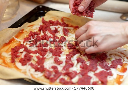 Hand chef puts on a pizza the chopped meat
