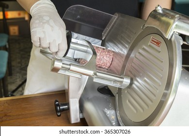 Hand Of Chef Wearing Rubber Glove For Good Hygiene Using Ham Slicer Machine