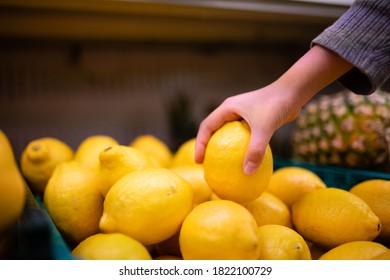 Hand of a child holding a lemon in a supermarket