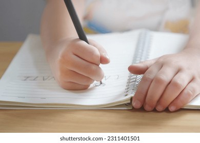 Hand of child practice writing on paper; preschool hand writing alphabet; kid drawing on notebook - Powered by Shutterstock