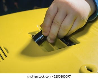 hand the child put the batteries panasonic in  yellow toy. Belarus,Minsk,2023 - Shutterstock ID 2250183097