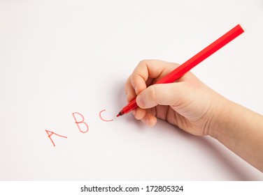 Hand eines Kindes, das Briefe auf weißem Papier schreibt