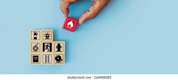 Hand choose cube wooden block stack with fire icon and door exit sing or fire escape with prevent icon and fire extinguisher and emergency prevention or protection symbol for safety and rescue. - Shutterstock ID 2169000283