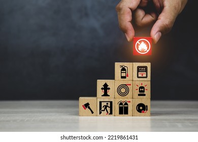 Hand choose cube wooden block stack with fire prevent icon with fire extinguisher for emergency protection and safety or rescue concepts in the building. - Shutterstock ID 2219861431