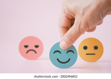 hand choose green paper cut, happy smiling face on pink background for mental health assessment ,positive thinking, world mental health day ,customer review, experience, satisfaction survey concept - Shutterstock ID 2002496852
