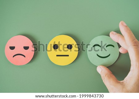hand choose green paper cut, happy smiling face on green background for mental health assessment ,positive thinking, world mental health day ,customer review, experience, satisfaction survey concept