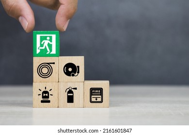 Hand choose wooden block stack with door exit sing or fire escape and fire prevent icon with fire extinguisher and emergency protection symbol for safety and rescue in the building. - Shutterstock ID 2161601847