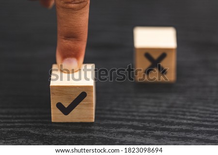 hand choose yes, true and blurred NO, false symbols on wood cube - True and false symbols accept rejected for evaluation
