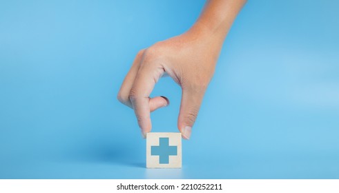 Hand Chooses A Emoticon Icons Healthcare Medical Symbol On Wooden Block, Insurance For Your Health Concept. Copy Space.