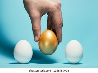 The Hand Chooses The Golden Egg Among The White Eggs.Concept Of Exclusivity, Best Choice, Hiring.